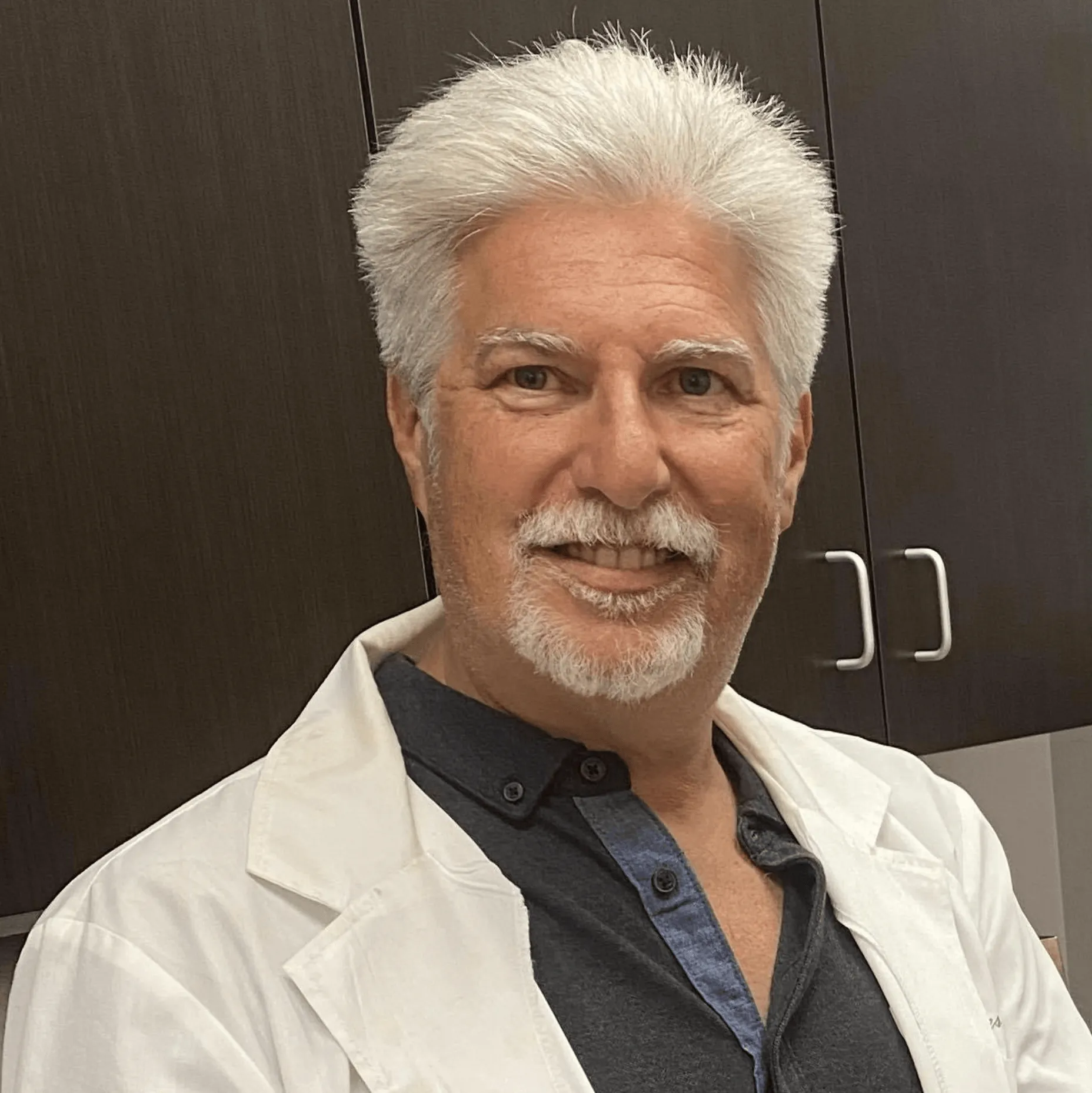 a man with white hair and a beard wearing a lab coat