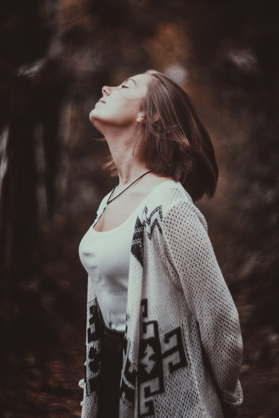 standing woman in white scoop-neck tank top with beige cardigan with her eyes close in selective focus photography afer ch9n liposuction